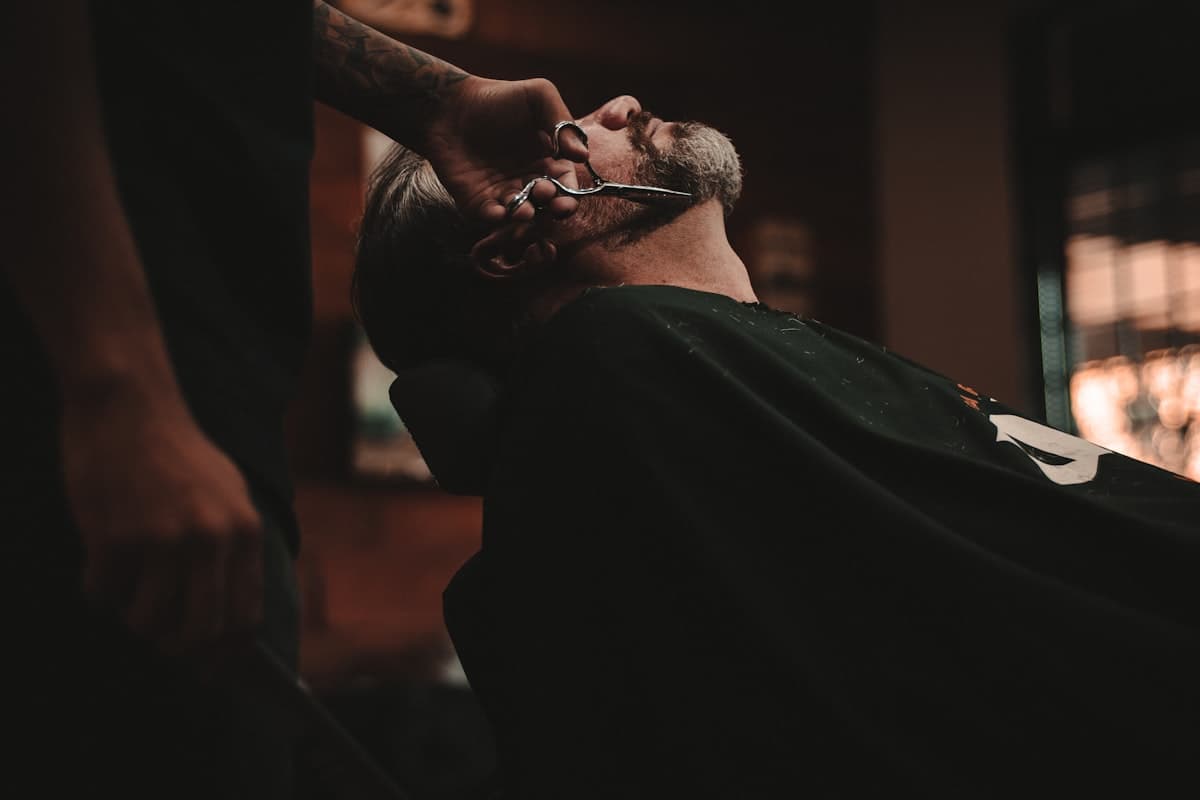 Barbero cortando el pelo a un cliente con navaja