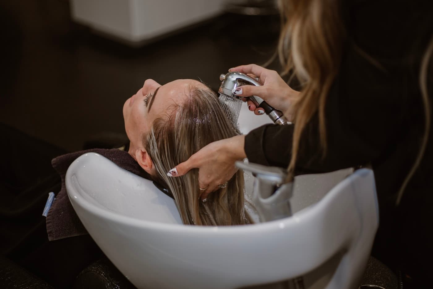 Estilista lavando el cabello a una clienta en una peluquería
