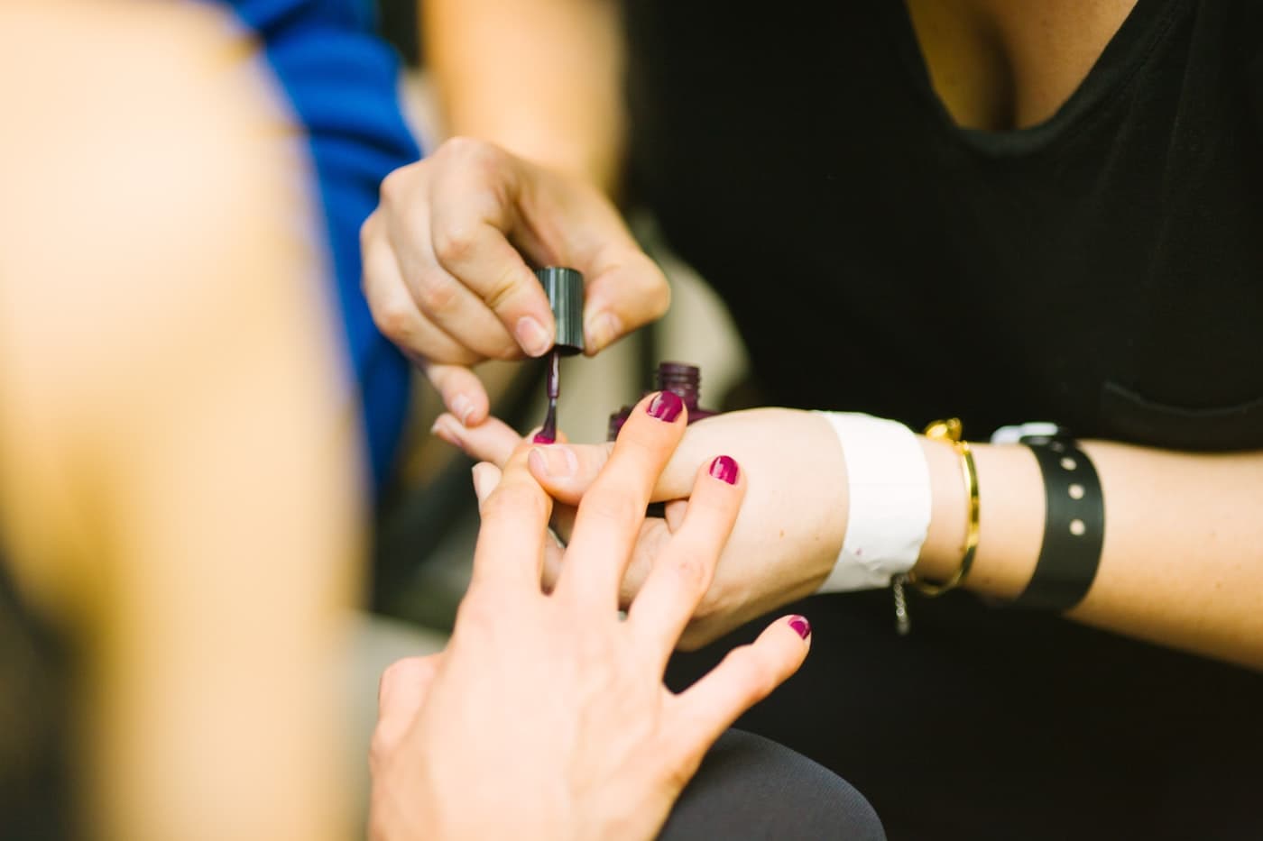 Manicurista pintando las uñas a una clienta con esmalte